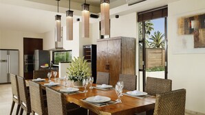 A dining area with a wooden table set for six, surrounded by wicker chairs, under pendant lights. - Villa Jamalu by Nakula (Jimbaran)