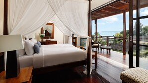 A bedroom with a canopy bed, a balcony with wooden flooring, and a view of the ocean. - Villa Jamalu by Nakula (Jimbaran)