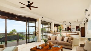 A spacious living area with a large wooden coffee table, beige sofas, and a view of the ocean. - Villa Jamalu by Nakula (Jimbaran)