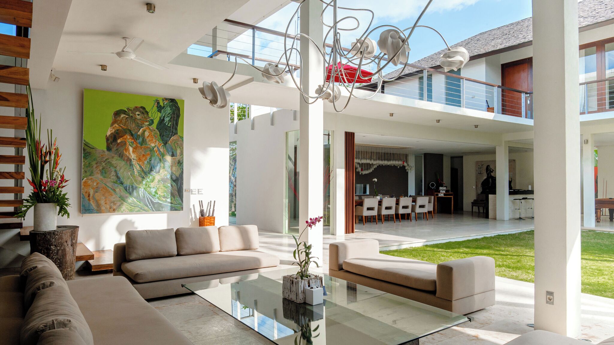 Een moderne woonkamer met een glazen salontafel, beige banken en een groot abstract schilderij.