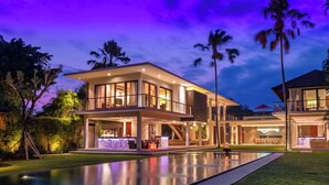 A modern two-story house with a large pool, outdoor seating, and a well-lit entrance. - Villa Kalyani (Canggu)