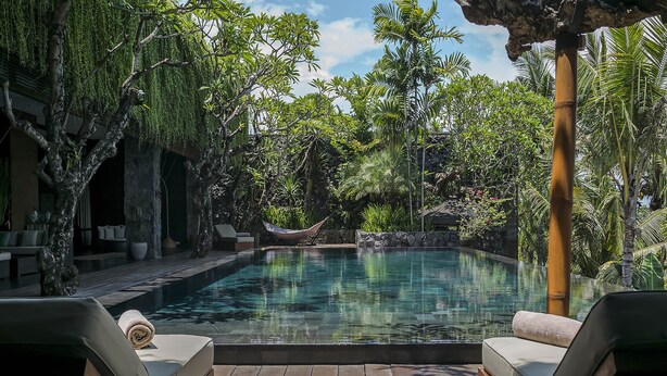 A pool area with lounge chairs, a hammock, and lush tropical vegetation. - Villa Mana by Elite Havens (Canggu)