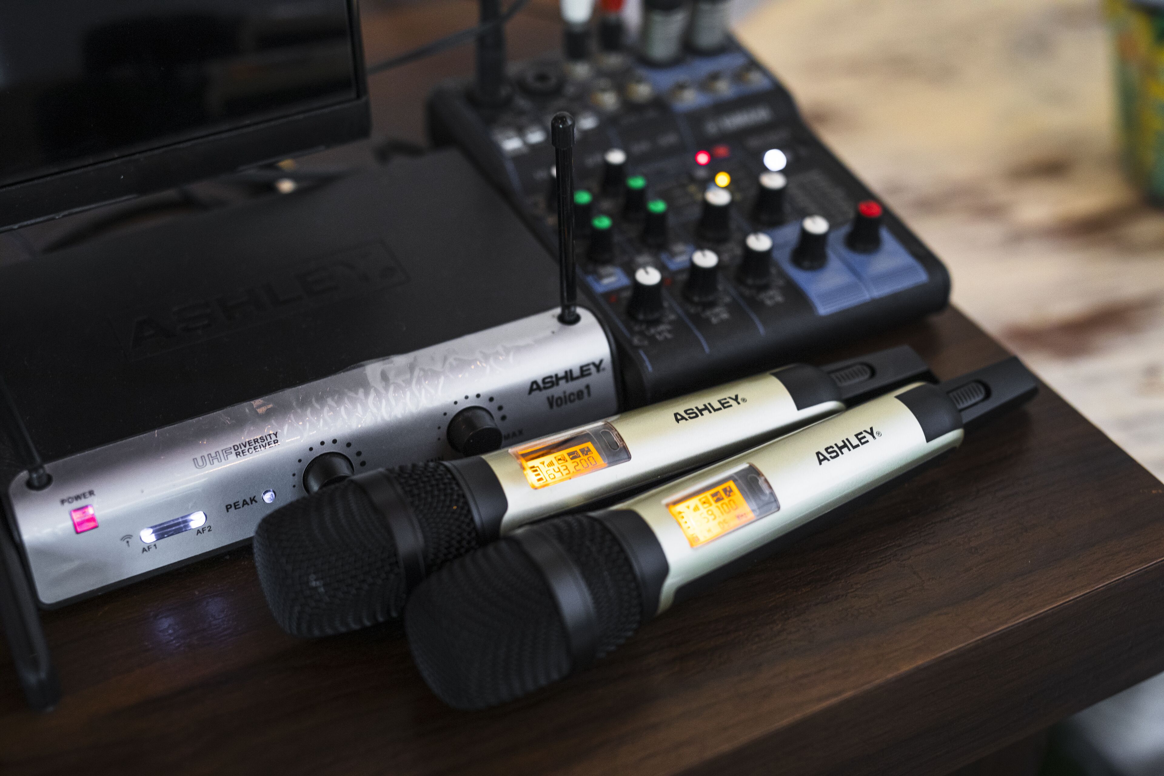 A microphone and audio mixer on a wooden surface.