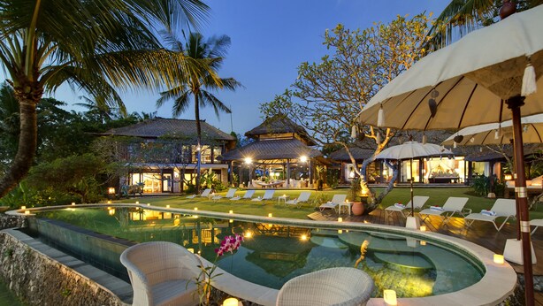 A luxurious resort with a swimming pool, lounge chairs, and a well-lit outdoor area.