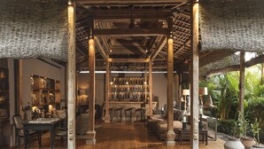 A spacious room with wooden flooring, a central bar area with shelves of bottles, and a seating area with chairs and tables. - Villa Zelie (Canggu)