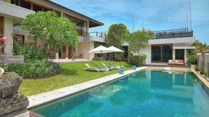 Uma casa moderna com piscina, gramado verde e área de estar ao ar livre.