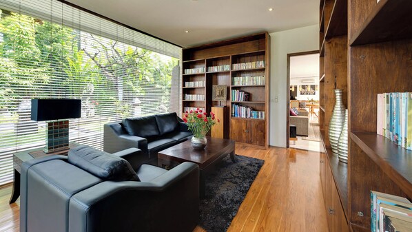 A modern living room with a black leather sofa, a coffee table, and a bookshelf filled with books.