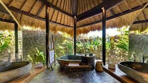 A spa area with stone flooring, two large sinks, a hot tub, and a stone wall with tropical plants. - Taman Ahimsa by Elite Havens (Cemagi)