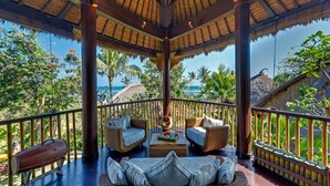 A covered outdoor seating area with wicker furniture and a view of the ocean. - Taman Ahimsa by Elite Havens (Cemagi)
