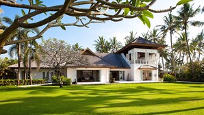 A large, two-story house with a spacious lawn, surrounded by palm trees and other tropical vegetation. - Villa Puri Nirwana (Gianyar)