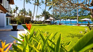A resort with a swimming pool, palm trees, and a well-maintained lawn. - Villa Puri Nirwana (Gianyar)