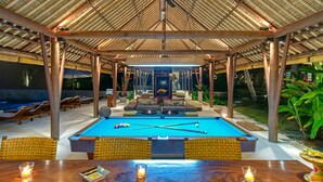 A pool area with lounge chairs, a pool table, and a covered seating area. - Villa Samadhana (Sukawati)