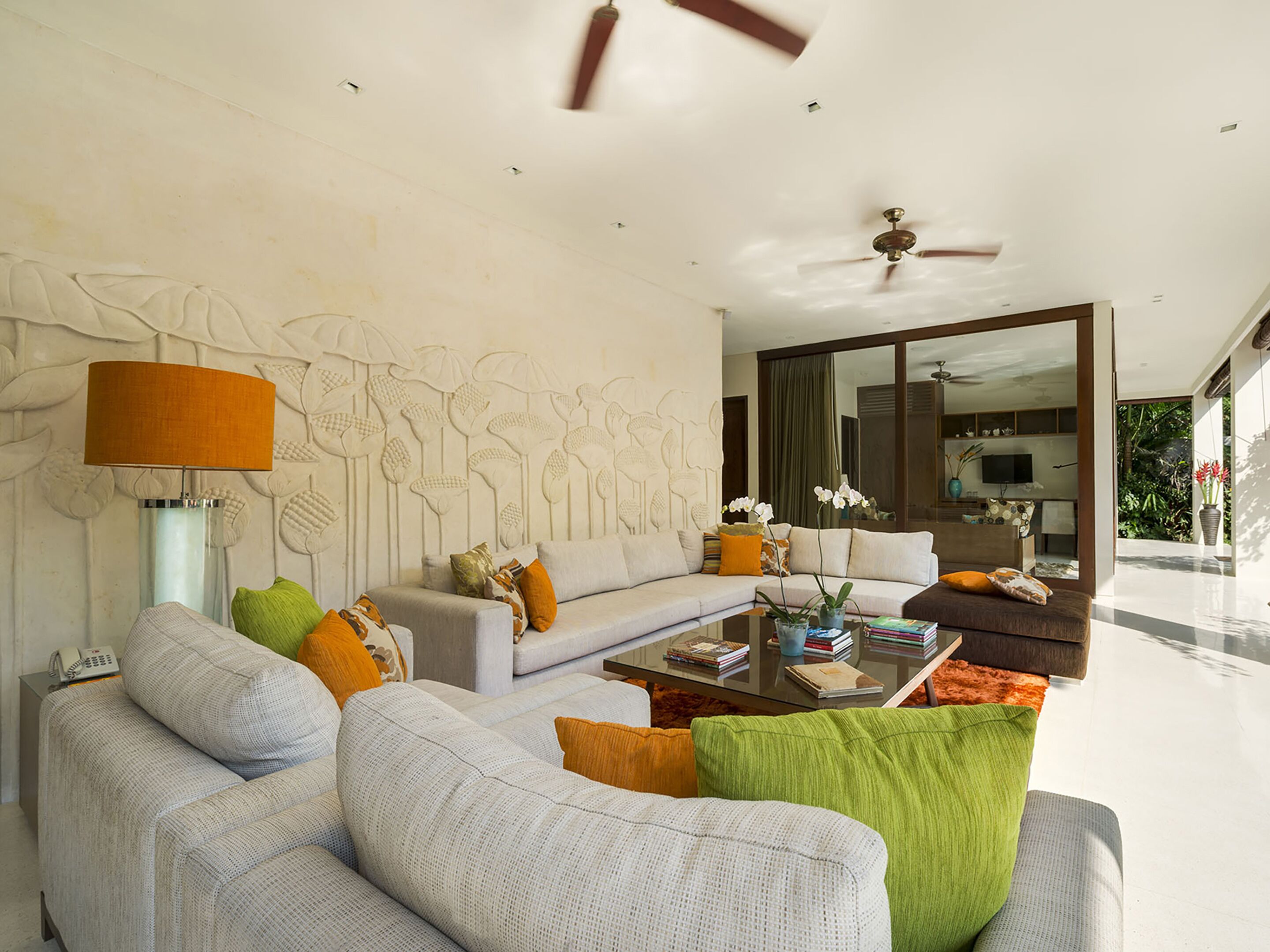 A modern living room with a sofa, armchairs, a coffee table, and a decorative wall.