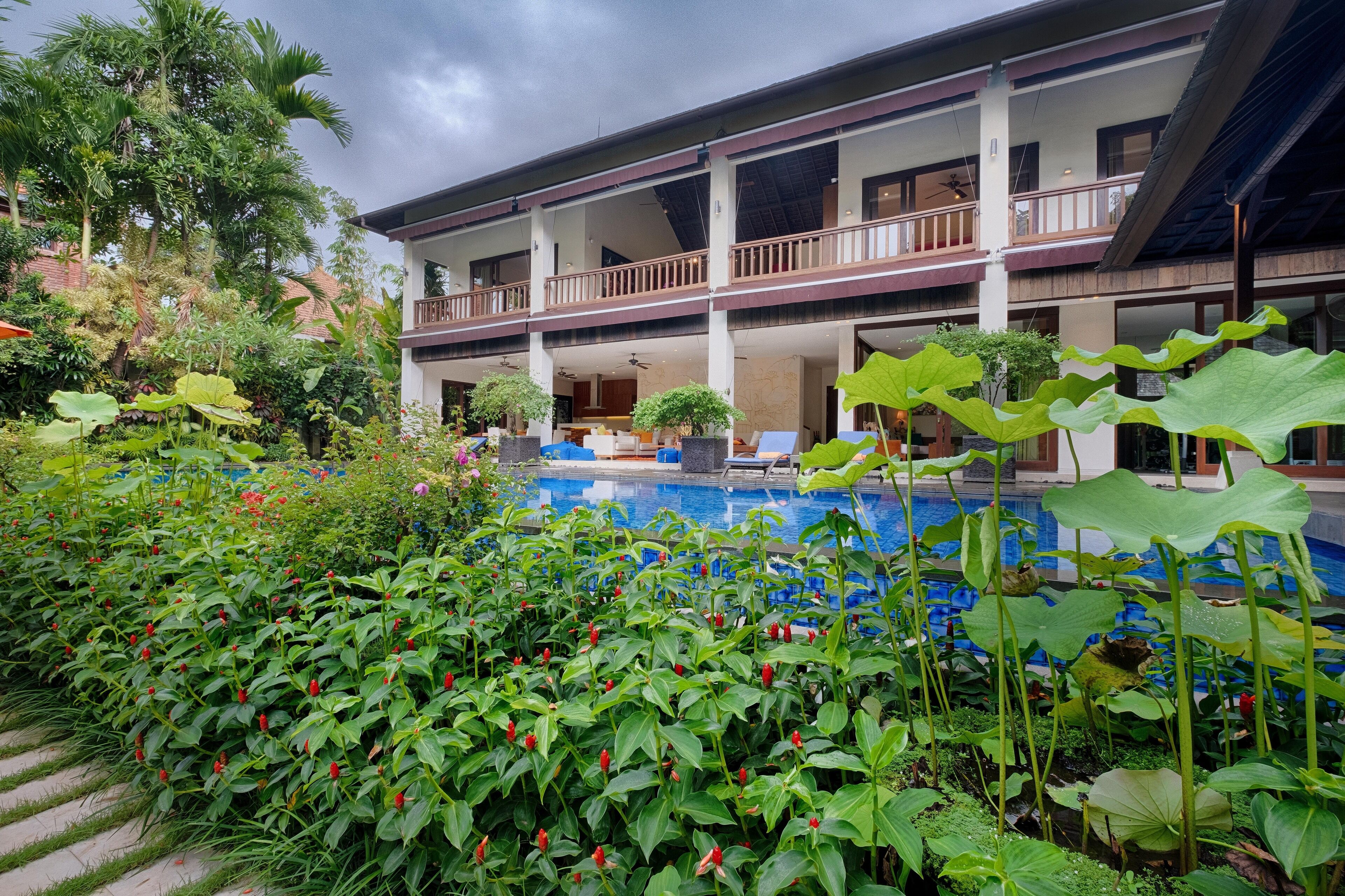 A hotel with a pool, lush greenery, and a multi-story structure with balconies.