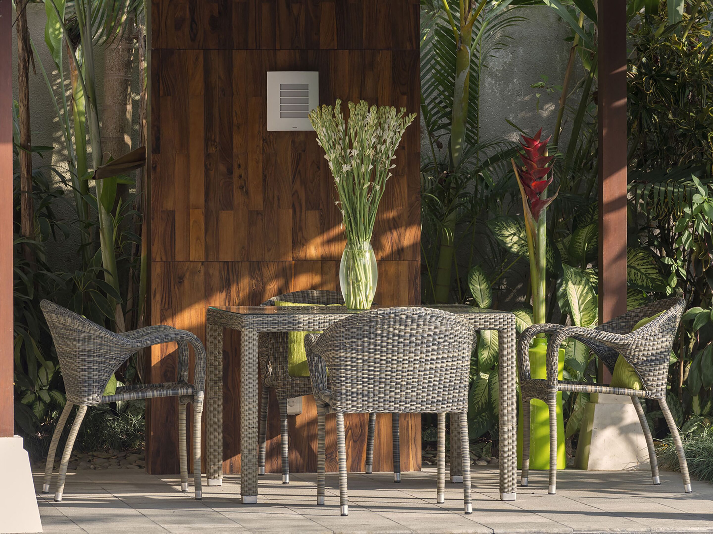 A patio area with wicker furniture, a table, and a vase of flowers.