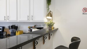 Eine moderne Küche mit weißen Schränken, einer schwarzen Arbeitsplatte, einem gelben Toaster und einem Rauchverbot-Schild an der Wand.