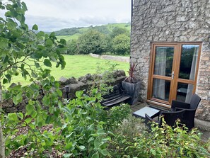 A stone building with a large window overlooking a green landscape.