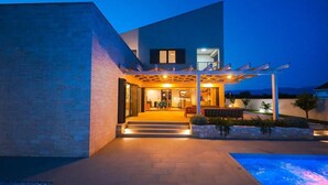 A modern house with a covered outdoor area, steps leading to the entrance, and a swimming pool. - Villa Petra (Nin)