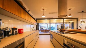 A modern kitchen with a central island, stainless steel appliances, and pendant lighting. - Villa Petra (Nin)
