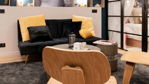 Un salon moderne avec un canapé noir, une table basse en bois et un coin repas comprenant une chaise en bois.