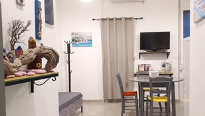 Une pièce moderne et bien éclairée, comprenant un coin repas, un lit et divers éléments de décoration murale.