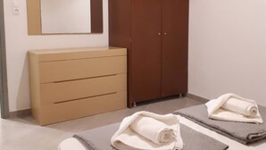 Une chambre avec une armoire en bois, un miroir et deux lits avec des serviettes.