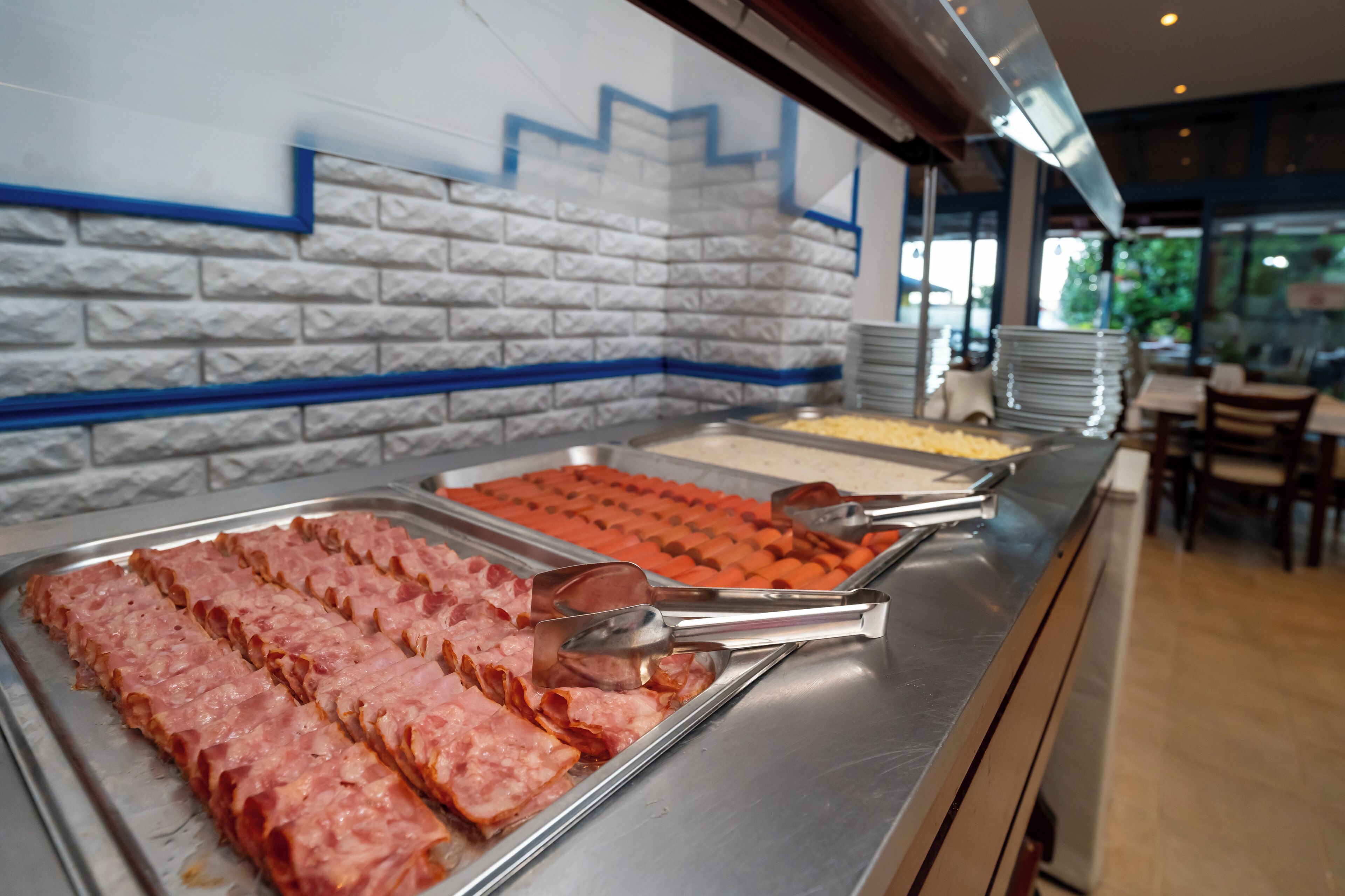 A buffet with various meats and a blue decorative wall.