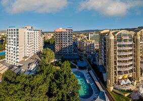 Un hotel de altura con múltiples balcones, una piscina y vistas de la ciudad circundante.