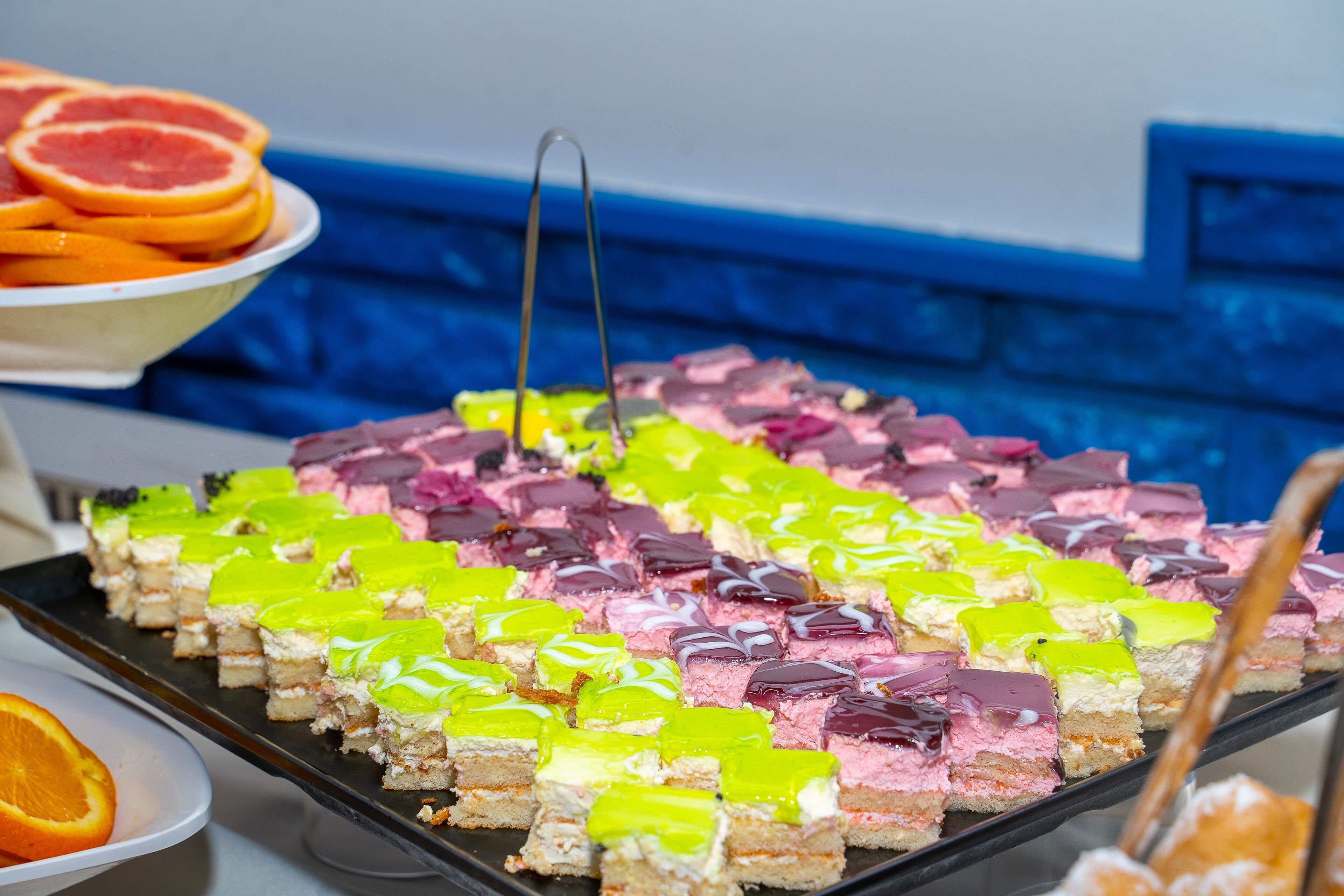 A tray of colorful dessert bars with a blue countertop in the background.