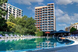 Un hotel con piscina, varios balcones y un cielo azul despejado.