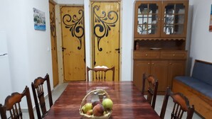 Un coin repas comprenant une table en bois, des chaises, un panier de fruits et des portes en bois ornées de motifs décoratifs.