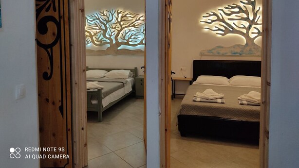 Une chambre avec deux lits, une porte en bois et des œuvres d’art décoratives au mur.