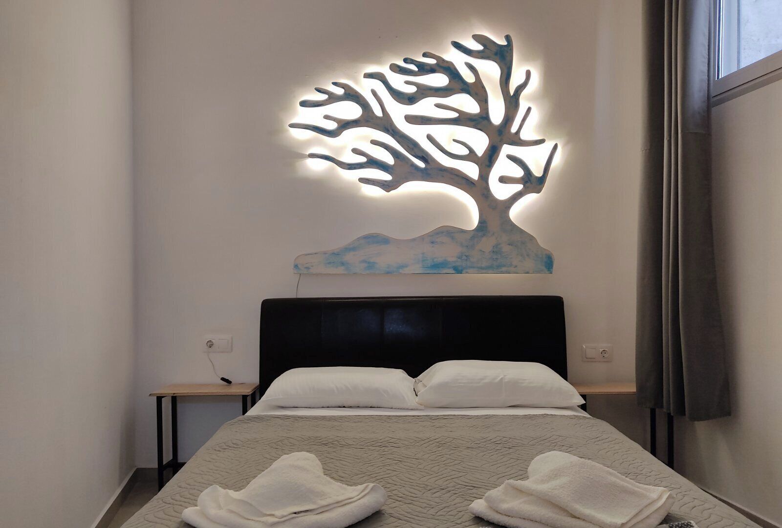 A neatly made bed with white linens and a folded towel on the bed.