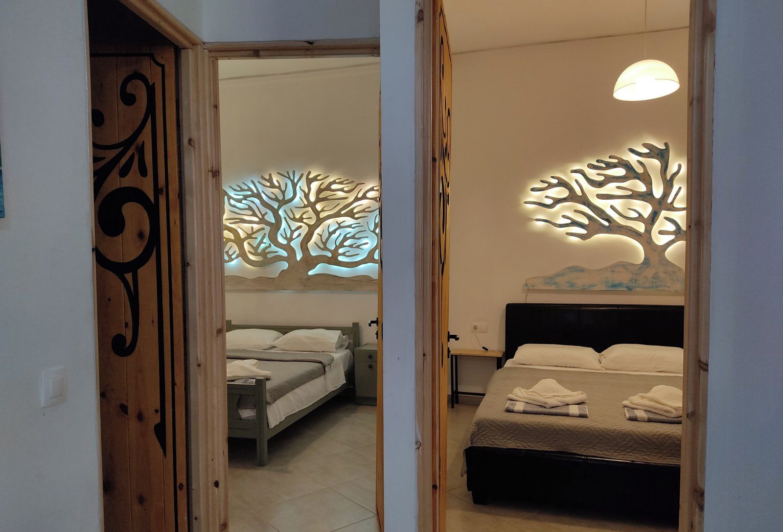 Un dormitorio con dos camas, una puerta de madera y detalles decorativos en la pared.