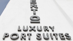 Een bord met de tekst 'EL CORTO LUXURY PORT SUITES', met een modern ontwerp en een goed zicht op de naam.