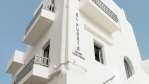 Een wit gebouw met balkons en een bord waarop staat 'EL PUERTO LUXURY PORT SUITES'.
