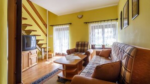 A living room with a sofa, a coffee table, a television, and a staircase. - Atrium Penzion (Poprad)