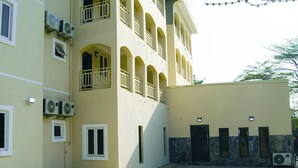 A multi-story building with balconies, air conditioning units, and a paved courtyard. - En Apartment (Abuja)