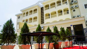 A hotel with multiple balconies, outdoor seating, and potted plants. - En Apartment (Abuja)