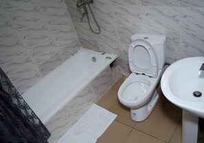 A bathroom with a bathtub, toilet, and sink. - En Apartment (Abuja)