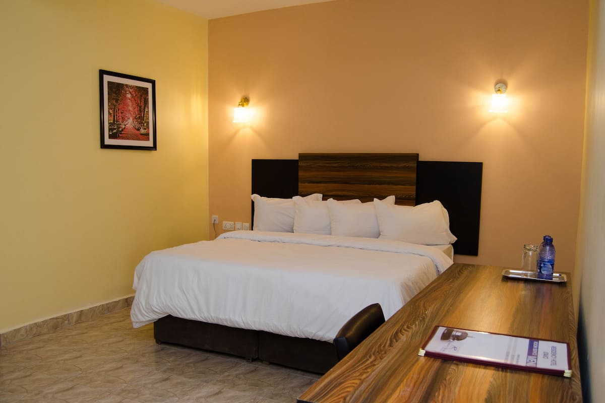 Une chambre d’hôtel avec un lit, une table de chevet et un tableau encadré au mur.