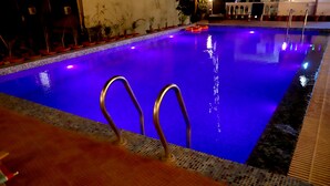 A swimming pool with a tiled edge and metal handrails. - Delhi Homes By Lujo Hotels (Narendranagar)