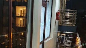 A corridor with a marble floor, large windows, and a balcony with railings. - Delhi Homes By Lujo Hotels (Narendranagar)