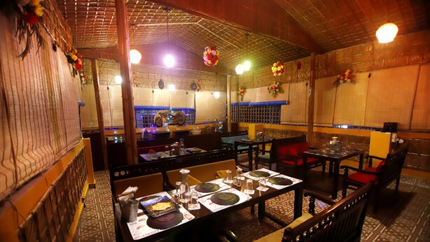 A restaurant with wooden interior, tables set for dining, and decorative elements on the walls. - Delhi Homes By Lujo Hotels (Narendranagar)