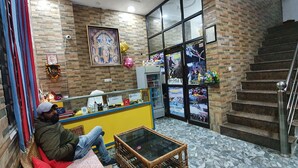 A reception area with a counter, a framed religious painting, and a staircase. - Delhi Homes By Lujo Hotels (Narendranagar)