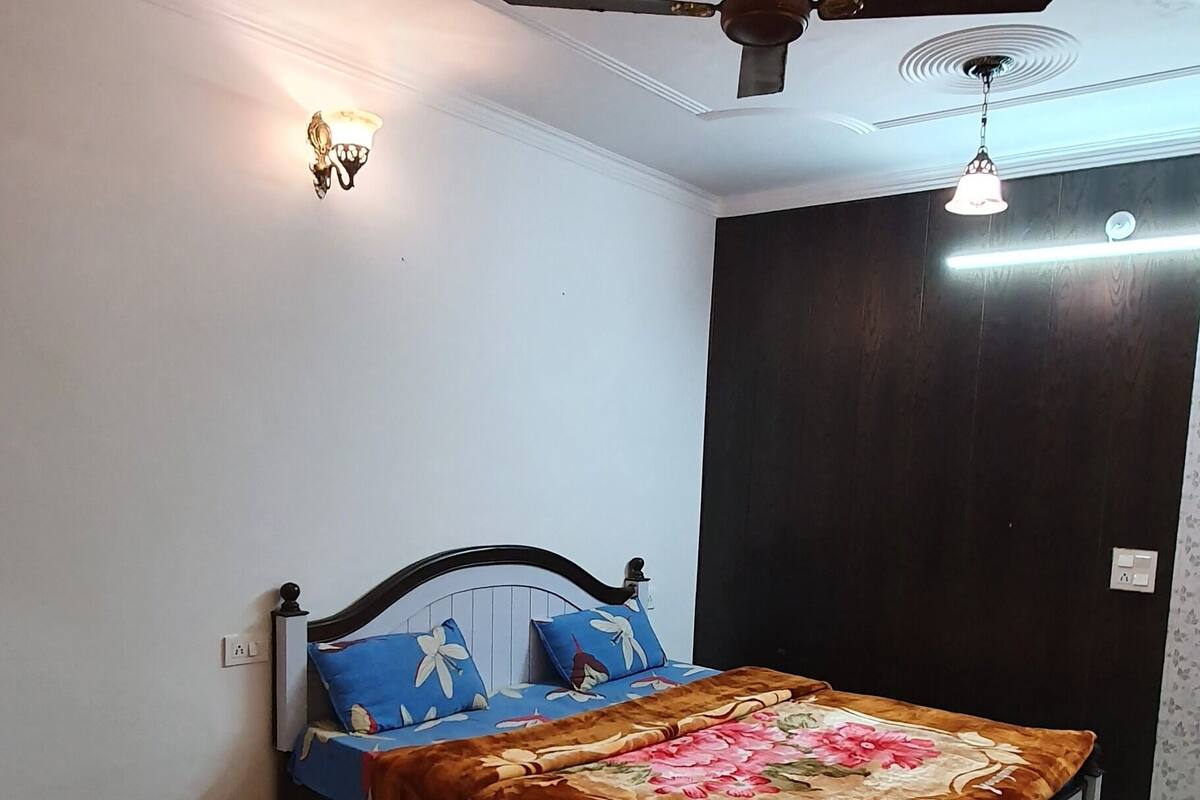 Une chambre à coucher comprenant un lit, un ventilateur de plafond, une lampe fixée au mur et un radiateur.