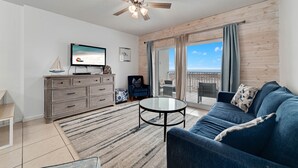 Una sala de estar moderna con ventilador de techo, televisor, sofá y vistas al exterior.
