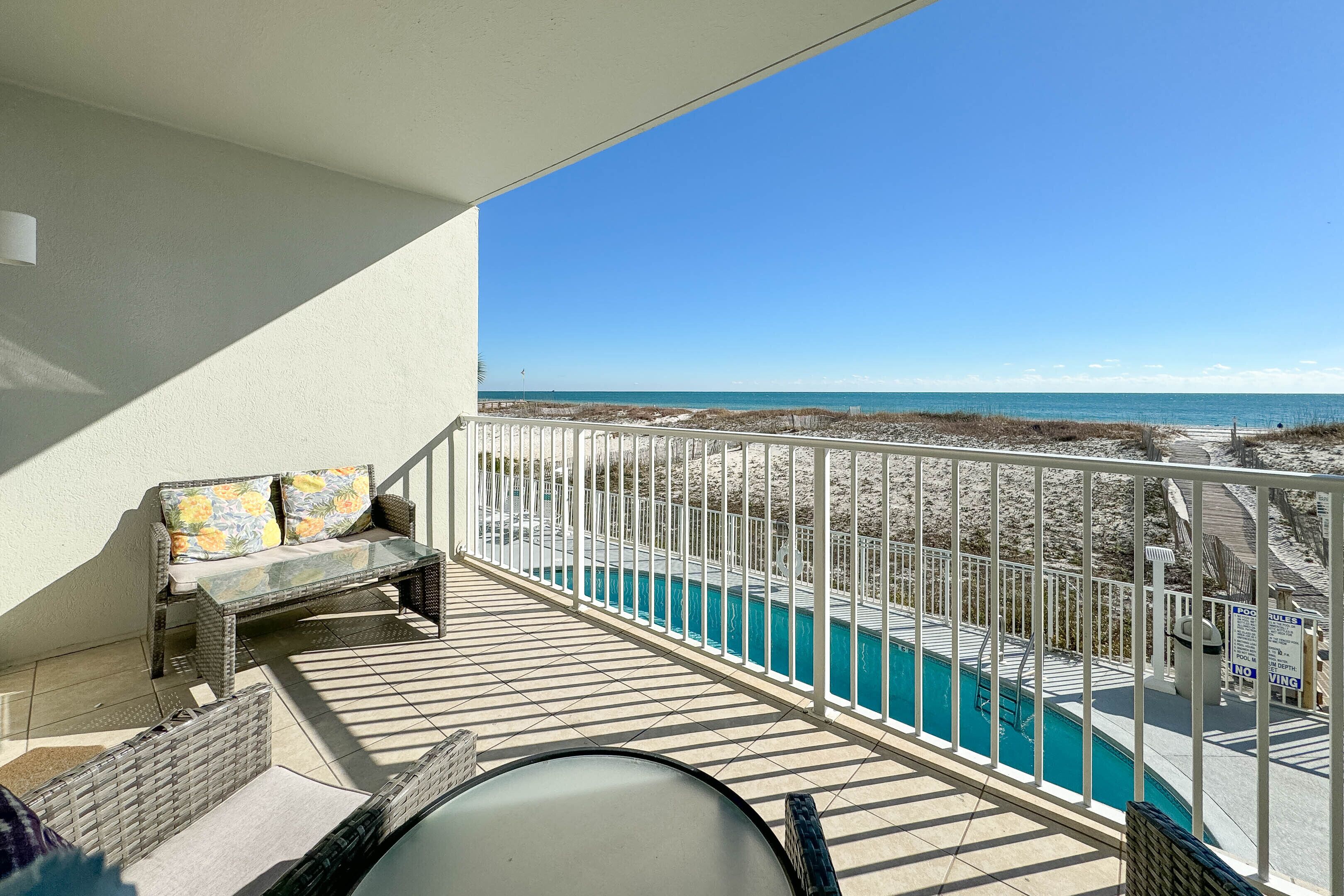 A balcony with a view of the beach and a swimming pool.