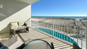 Un balcón con vista a la playa y a una piscina.