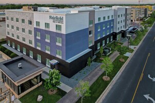 Un hotel de varios pisos con un diseño moderno, que combina fachadas de ladrillo y vidrio, y un área de estacionamiento en la azotea.